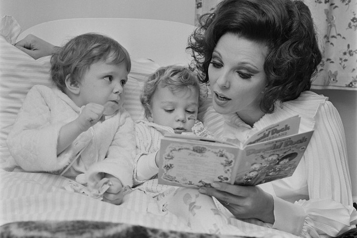 English actress Joan Collins, the wife of actor and singer Anthony Newley, reading a Donald Duck book to their two children Tara and Sacha, UK, 18th November 1967.  (Photo by Dove/Daily Express/Getty Images)