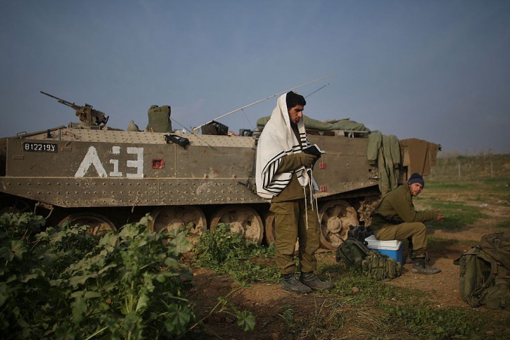 An Israeli soldier, just back from Gaza, prays beside his armored personnel carrier (APC) on January 17, 2009 along the Gaza-Israeli border in Israel.  (Photo by Spencer Platt/Getty Images)