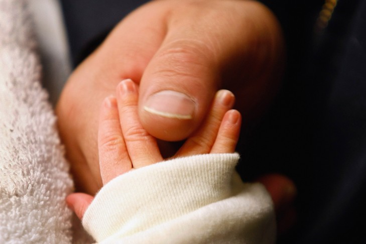 A father touches his newborn son's hand.  (Photo by John Moore/Getty Images)