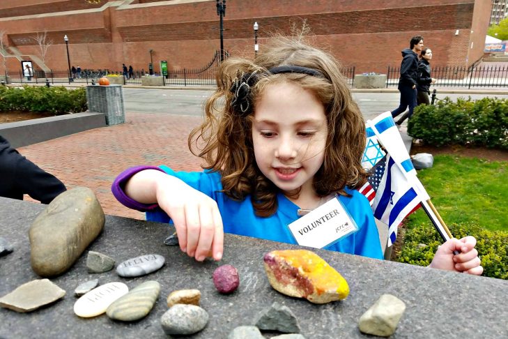 Sophie Einstein, 5, places a rock at the New England Holocaust Memorial during the community Holocaust commemoration of Yom HaShoah on Sunday. (Photo courtesy of Boston 3G)