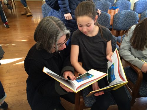 student showing her paintings in the final siddur to her mother