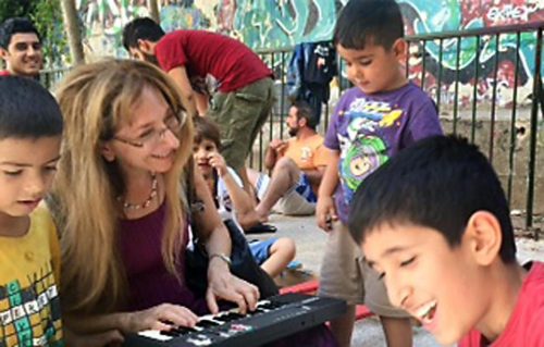 Judy Stillman, a professor of music at Rhode Island College, played a miniature keyboard for children at a refugee camp outside of Athens. (JUDY STILLMAN)