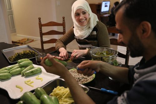 Asmaa made stuffed grape leaves with her husband in their kitchen. Abdulkader used bits of squash to practice his English letters, spelling out JFS, the acronym for his resettlement agency.