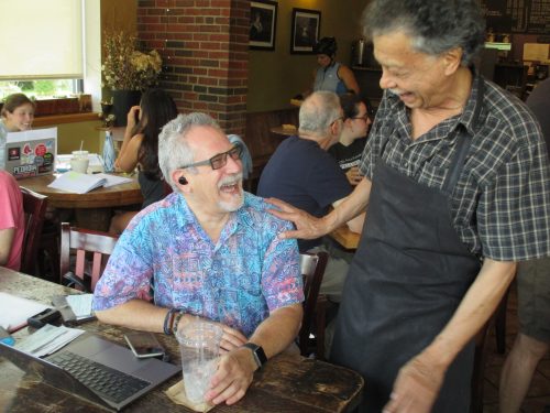 Stephen Weil, an Arlington technology entrepreneur, takes a break from working at his laptop to share a laugh with Boanerges Martinez, part of the weekend crew at Kickstand who welcomes all comers. Weil, who is Jewish, a regular at Kickstand, has lived in Arlington for decades and recalls past efforts to create some organized Jewish community or center.