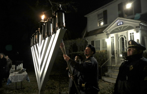 referral use only Needham police officer Matthew Palmer lit the first candle. Rabbi Mendy Krinsky is at his right.PAT GREENHOUSE/GLOBE STAFF/GLOBE STAFF