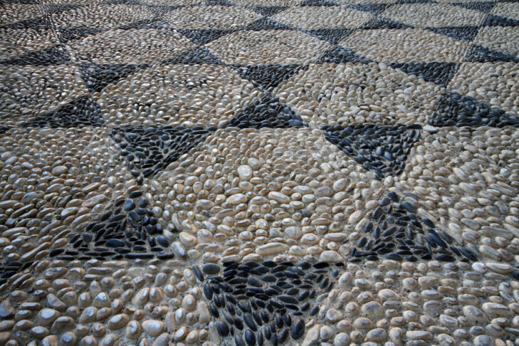 Floor mosaic of gray and black stones in the form of six-pointed stars.