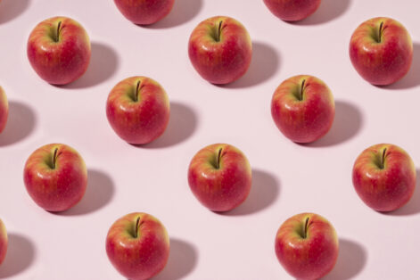 Red apple fruit in a row on pink pastel background