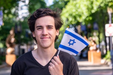 Smiling young man waving the Israeli flag looking at the camera