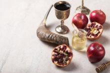 Rosh hashanah - jewish New Year holiday concept. Traditional symbols: Honey jar and fresh apples with pomegranate and shofar-horn,  on a concrte   background. Copy space for text. View from above