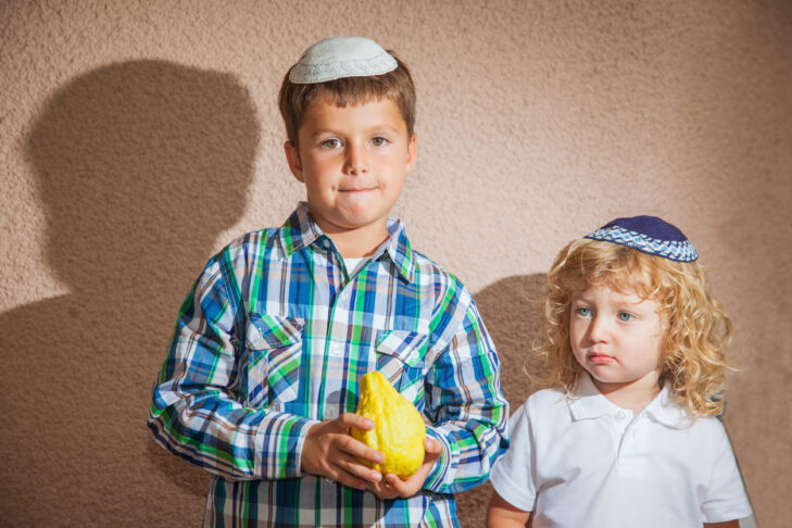 The Jewish holiday of Sukkot. Two boys in yarmulkes. The older boy is holding the etrog