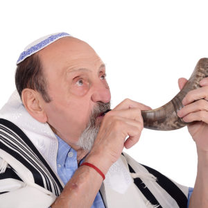 Eldery jewish man blowing the Shofar horn for the Jewish New Year holiday (Rosh Hashanah). Religion concept. Isolated white background
