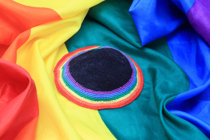 Rainbow colored yarmulke over rainbow flag