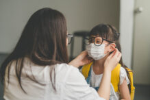 Image of Asian mother help her daughter wearing medical mask to prepare go to school. Avoiding Covid-19 or coronavirus outbreak.