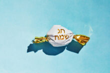 Candy cane with the inscription in Hebrew - Happy holiday. The concept of the Rosh Hashanah holiday - the Jewish New Year.