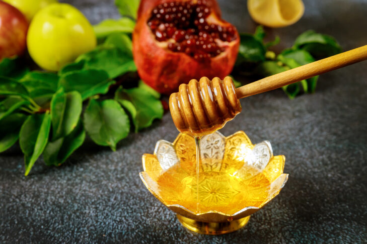 Natural sweet honey with wooden honey stick and pomegranate.