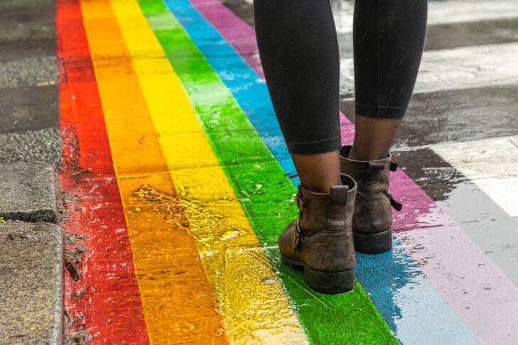 Female legs walking on rainbow crosswalk in Gay parade.