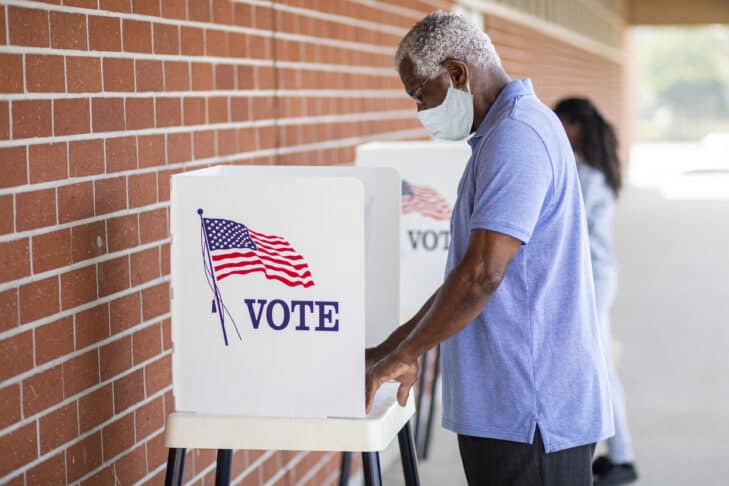 A senior black man casts his ballot on election day.