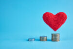 Red heart flying under coin stacks over the blue background. copy space. money coins stairs to love and romance concept. love to money concept.