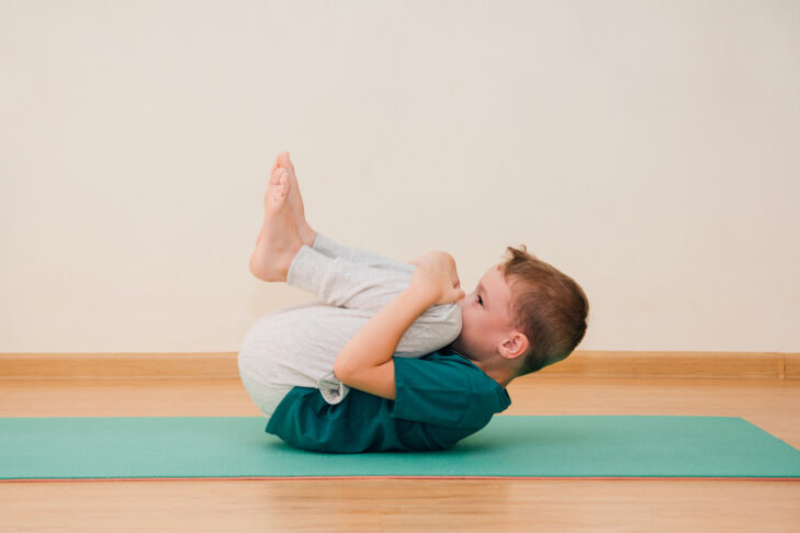 Cute little boy is learning to do yoga in the gym. The concept of sport and healthy lifestyle.