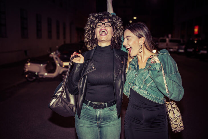 Two young drunk female friends on city street after party