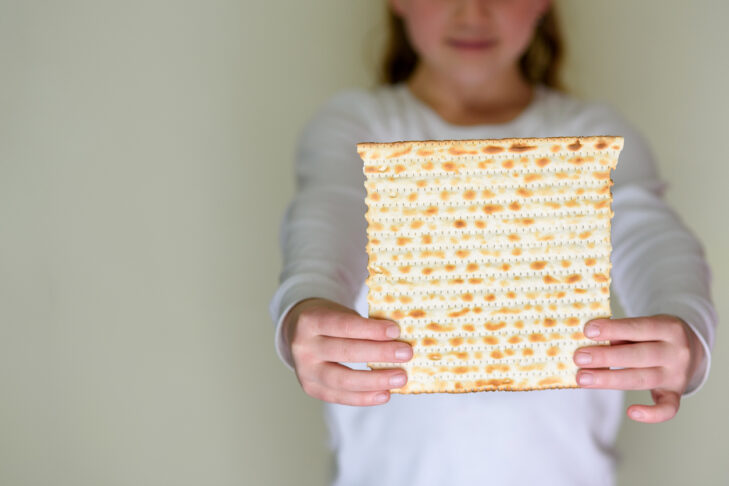Young girl holding matzah or matza. Jewish holidays Passover invitation or greeting card.Selective focus.Copy space.