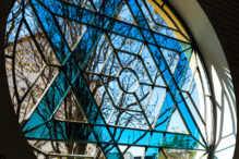 Close up color image depicting a Jewish Star of David stained glass window inside a synagogue. Room for copy space.