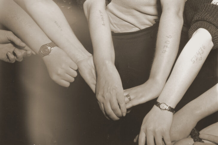 Jewish women liberated from a factory in Mehlteuer display their tattoos (United States Holocaust Memorial Museum, courtesy of National Archives and Records Administration, College Park)