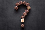 Question mark created from pieces of chocolate candies on the dark table. Choice of the best sort and quality. Dieting questions and worries concept about sweet food. Tasty temptation.