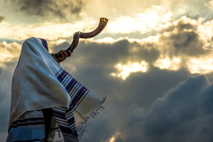 Jewish person in a tallith prayer shawl against dramatic sky