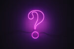 Question mark symbol drawn by purple neon light on black wall. Horizontal composition with copy space.