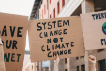 Group of people participating in a protest against global warming. Climate change protest concept. They are holding banner signs.