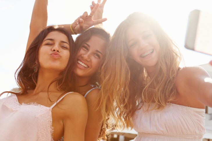 Three Teenage Girls Dancing And Taking Selfie Looking To Camera