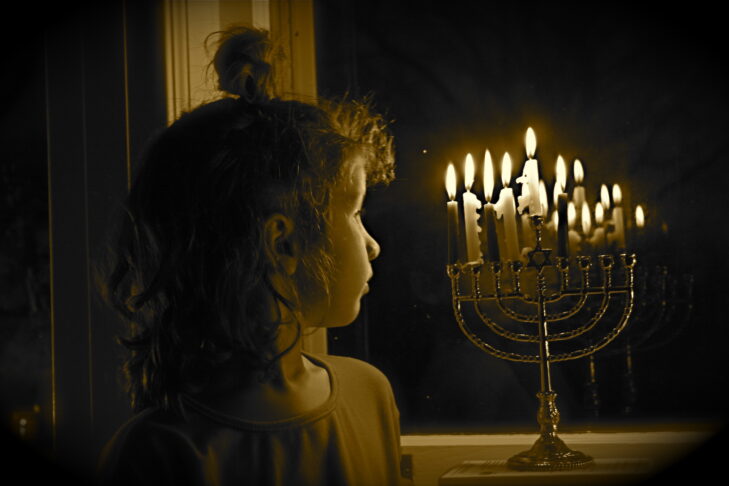 girl on hanukkah looking at Menorah