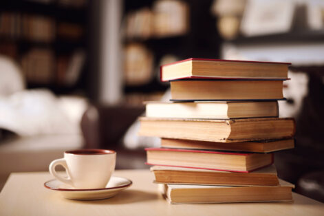 Stack of books and coffee or tea, reading stack of books in home interior