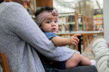 Baby sits in mother's lap during a young mother's support group meeting
