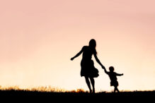 Mother and child dancing, kid dance Silhouette of a happy mother and her baby daughter holding hands, and running and dancing outside at sunset.