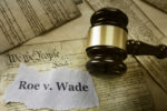Roe v Wade news headline with gavel on a copy of the United States Constitution