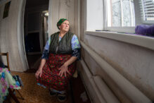 Indoor photo. Woman is looking at window. She is waiting for her grand kids.