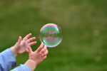 Large Bubble Being Caught by a Young Child Outside in the Spring Close Up Abstract
