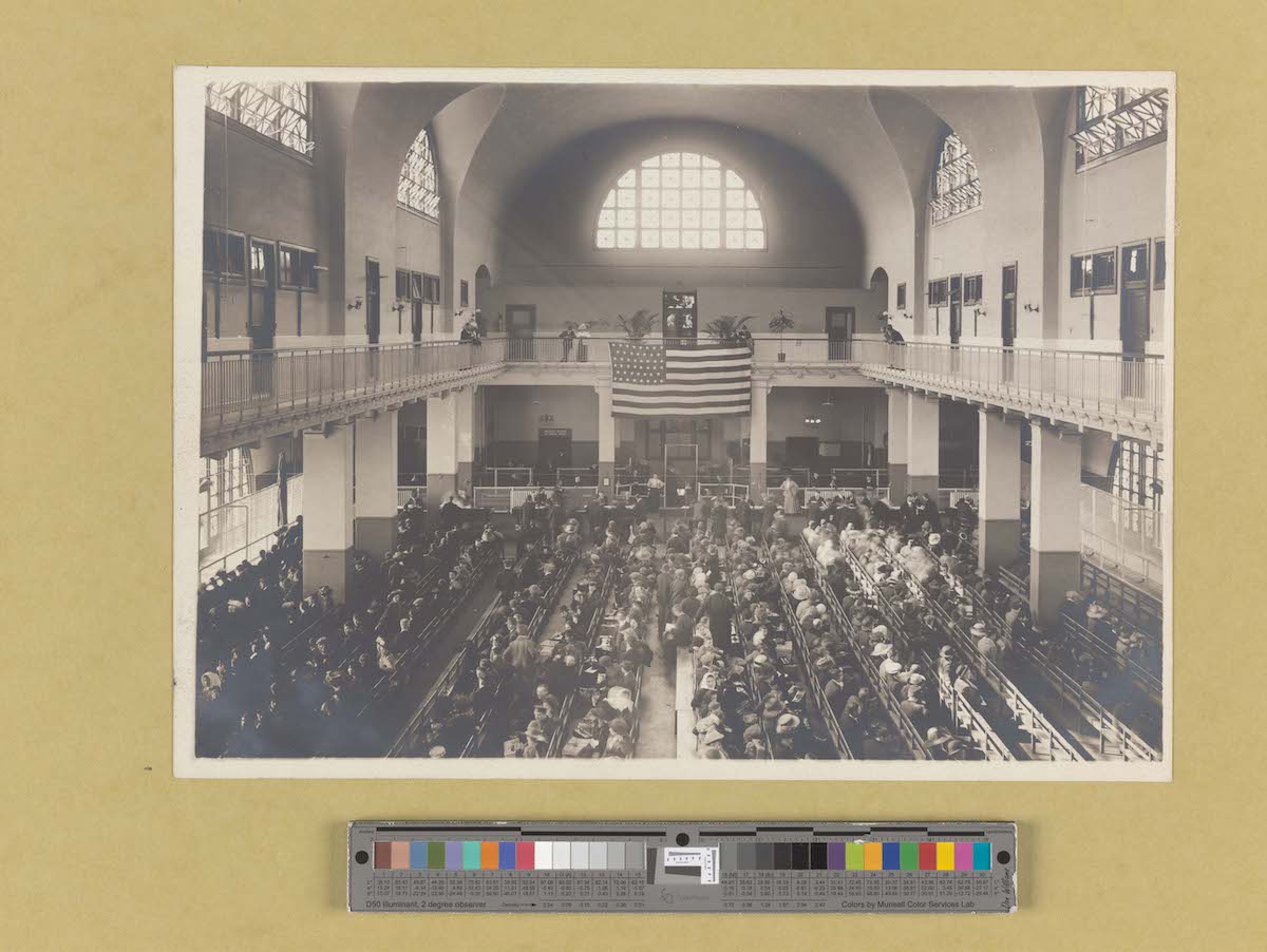Immigrants seated on long benches, Main Hall, U.S. Immigration Station. RLIN/OCLC: NYPG95-F135 NYPL catalog ID (B-number): b12326658