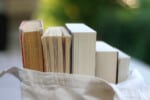 Canvas tote bag filled with books in the garden. Selective focus.