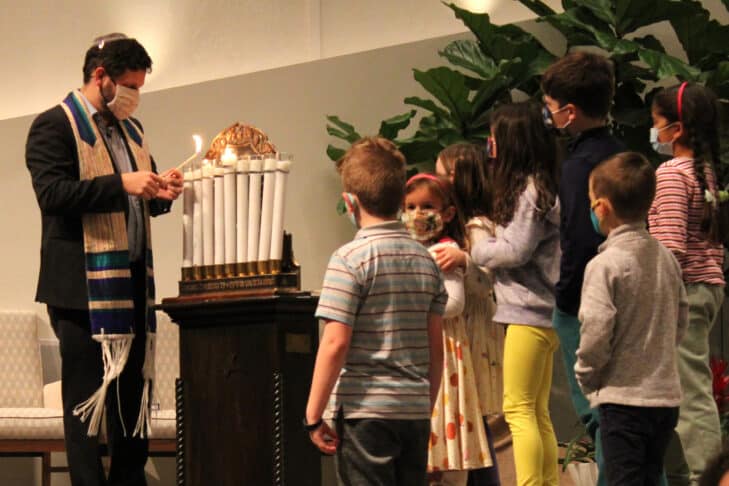 Rabbi Slipakoff lighting Chanukah candles wth a group of young children