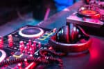 DJ music console in bright colors of light in night club bright background