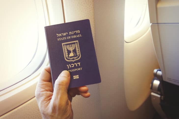 Detail of passenger's hand holding passport of the state of Israel on the airplane