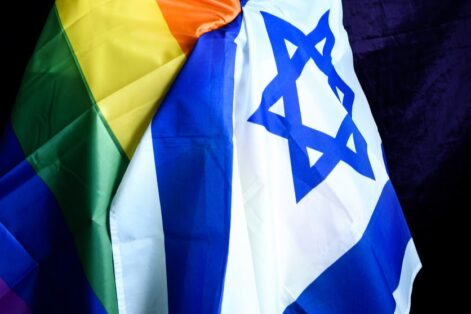 Adult gay man with shaved head posing with LGBT and Israeli flags