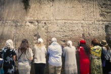Jerusalem, Israel - August 2018: Women praying at the Western Wall, which is one of Judaism most holy places and located in the old city of Jerusalem. The wall is cracked and in the cracks are pieces of paper with prayer notes.
