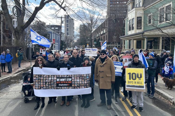 CJP President and CEO Rabbi Marc Baker holds a banner with Israeli hostages' faces, in front of and alongside other members of the community