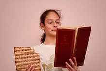 Passover Haggadah Portrait of the cute teenager girl holding matzah and reads the Passover Haggadah. Jewish child eating matzo unleavened bread in Jewish holidays Passover.