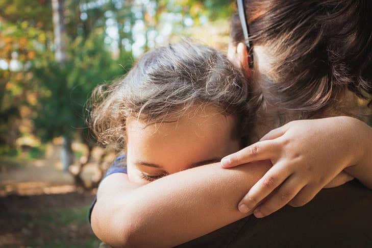 Close-up of embraced mother and daughter. Close-up of little girl embracing her mother with eyes closed.
