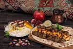 Traditional Middle eastern Persian chicken and lamb meat Shashlik Kebab (skewered meat) BBQ Grill on flat pita bread and saffron rice and tahchin and pomegranate on a dark background. Iranian cuisine Traditional Middle eastern Persian chicken and lamb meat Shashlik Kebab (skewered meat) BBQ Grill on flat pita bread and saffron rice and tahchin and pomegranate on a dark background. Iranian cuisine
